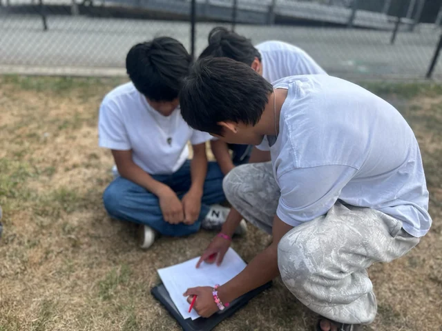 Students working together over a worksheet outdoors at Carlmont High School.