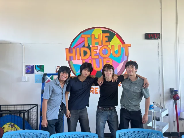 Four TimeBack team members in front of the Hideout Hub mural.