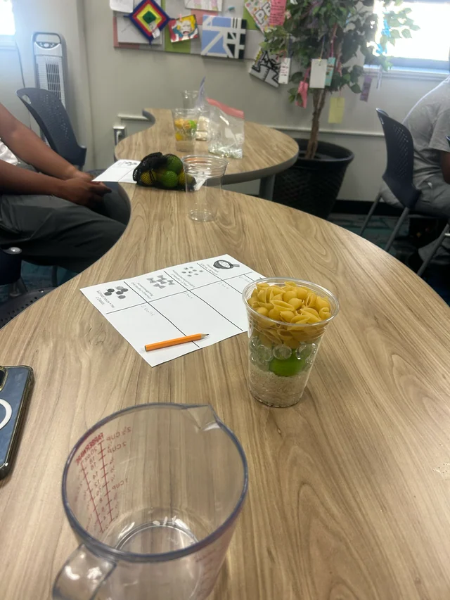 A container of activity materials beside a worksheet.